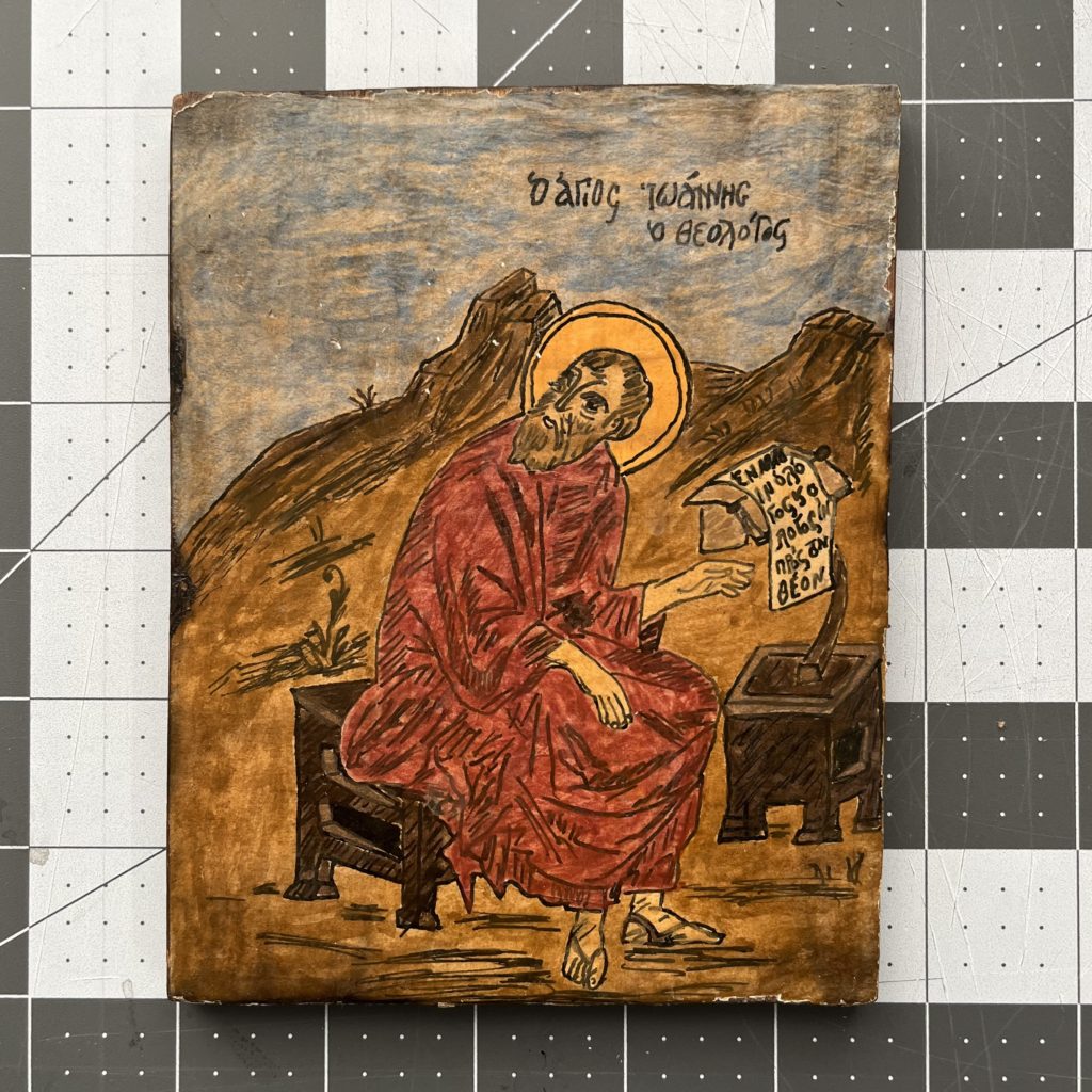 A photo of a homemade icon of St John the Theologian against a grid of gray and white squares.